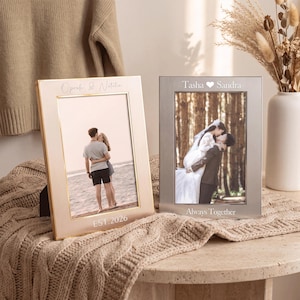 May include: Two rectangular photo frames with personalized engravings. The left frame is rose gold with 'Oprah & Natalie' and 'EST. 2026' text. The right frame is brushed silver with 'Tasha ♥ Sandra' and 'Always Together' text, each displaying a couple.