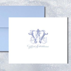 May include: A white card with a blue monogram of the letters "KW" in a decorative font. The name "Kimberly Williams" is written in cursive below the monogram.