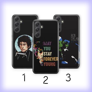 May include: Three black phone cases with different designs featuring Bob Dylan. The first case has a portrait of Bob Dylan with a harmonica. The second case has a portrait of Bob Dylan with the text "May You Stay Forever Young". The third case has a portrait of Bob Dylan with the text "Bob Dylan" and "Blowin' in the Wind".