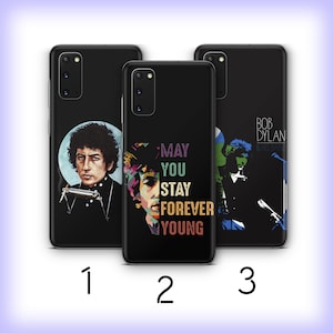 May include: Three black phone cases with different designs featuring Bob Dylan. The first case has a portrait of Bob Dylan. The second case has a portrait of Bob Dylan with the text "May You Stay Forever Young". The third case has a silhouette of Bob Dylan with the text "Bob Dylan & His Band".