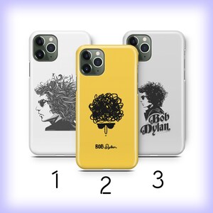 May include: Three different phone cases featuring a black and white illustration of Bob Dylan. The first case is white with a portrait of Bob Dylan. The second case is yellow with a stylized illustration of Bob Dylan's hair. The third case is white with a portrait of Bob Dylan and the text "Bob Dylan".