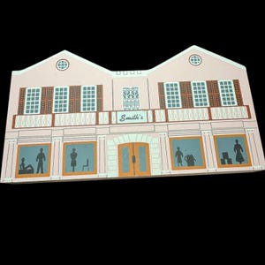 Puede incluir: Un edificio rosa de dos pisos con contraventanas marrones y el nombre "Smith's" sobre la entrada. El edificio tiene un balcón blanco y columnas decorativas. Se ven siluetas de personas en las ventanas.