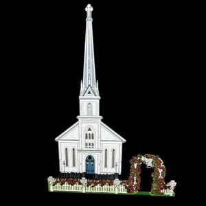 May include: A white church with a tall steeple, blue door, and a white picket fence. A floral archway with red roses and white bows is to the right of the church. The church is a decorative item.