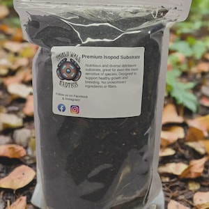 May include: A clear, resealable plastic pouch filled with dark, coarse organic substrate. A white rectangular label on the front features the Shield Wall Exotics logo, the text Premium Isopod Substrate, and social media icons for Facebook and Instagram.