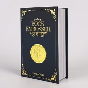 May include: A navy blue book embosser with gold lettering and decorative corner designs. The text on the cover reads "Book Embosser" and includes a gold seal with a sword design. The book's pages are white.