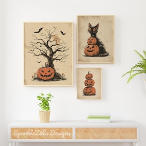May include: Set of three framed Halloween art prints. One features a tree with a jack-o'-lantern, bats, and a full moon. Another shows a black cat atop two carved pumpkins. The third print displays a stack of three carved pumpkins.