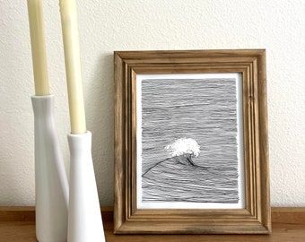 May include: A black and white line drawing of a wave crashing, framed in a natural wood frame. The frame is sitting on a wooden surface with two white candle holders and candles.