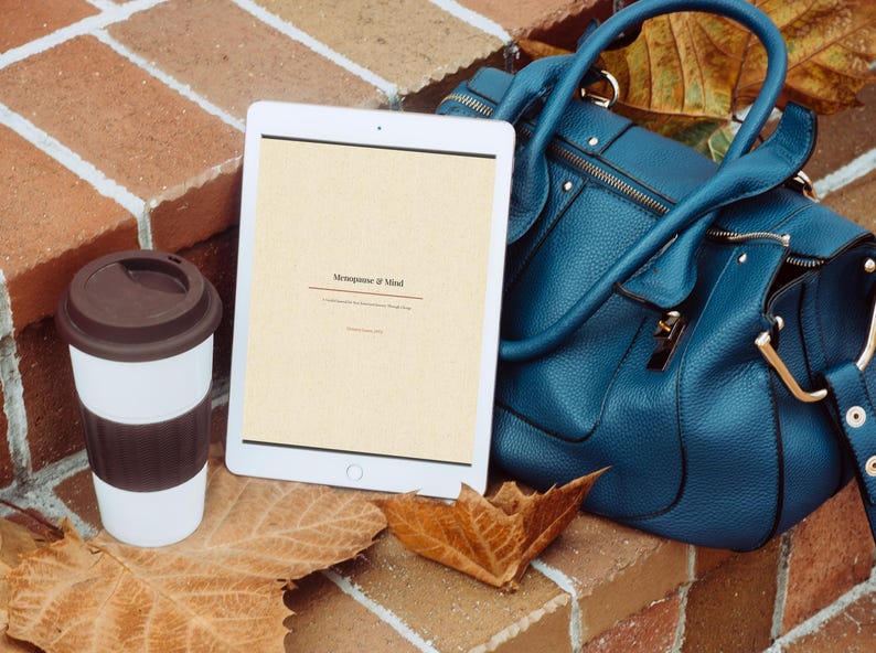May include: A white tablet displaying the text Menopause & Mind, a white and brown travel coffee cup with a lid, and a textured teal blue handbag. The items are arranged together, with the tablet screen showing clear black text on a light background.