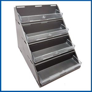 May include: A gray tiered display stand with five clear plastic shelves. The stand is angled and has a modern design.