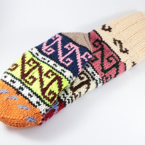 May include: Multicolored knitted wool socks with a geometric pattern. The socks are folded and show the different colors and patterns.