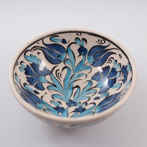 Puede incluir: Un cuenco de cer&aacute;mica blanca con un dise&ntilde;o floral azul y turquesa. El cuenco est&aacute; pintado a mano con detalles intrincados y presenta un patr&oacute;n turco tradicional.
