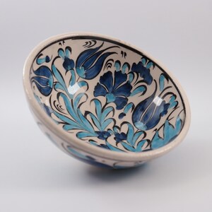 Puede incluir: Un cuenco de cer&aacute;mica blanca con un dise&ntilde;o floral azul y turquesa. El cuenco est&aacute; decorado con tulipanes y hojas estilizadas.