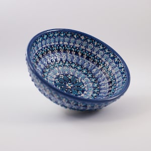 May include: A blue and white ceramic bowl with a decorative pattern. The bowl is round and has a slightly raised rim.