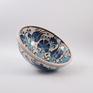 Puede incluir: Un cuenco de cer&aacute;mica blanca con un patr&oacute;n floral azul y turquesa. El cuenco est&aacute; decorado con flores y hojas estilizadas.