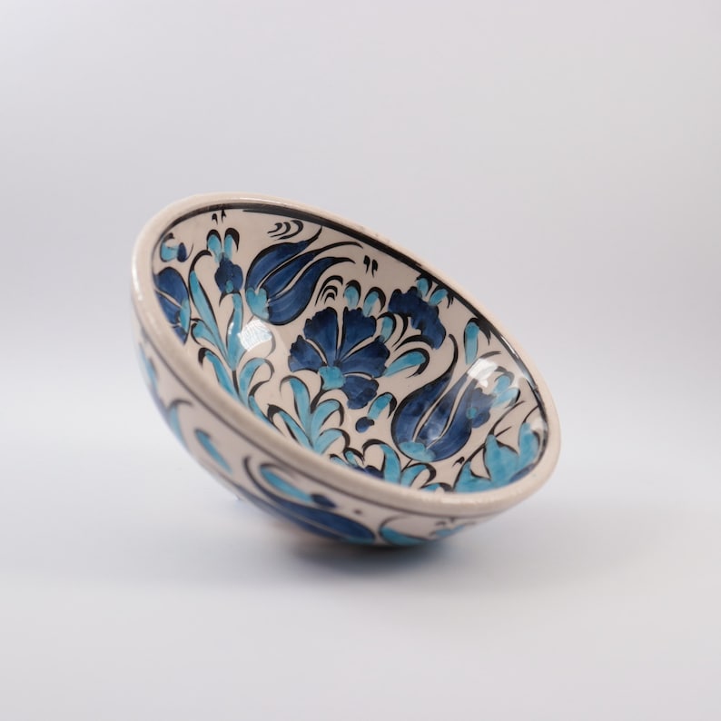 Puede incluir: Un cuenco de cer&aacute;mica blanca con un patr&oacute;n floral azul y turquesa. El cuenco est&aacute; decorado con flores y hojas estilizadas.