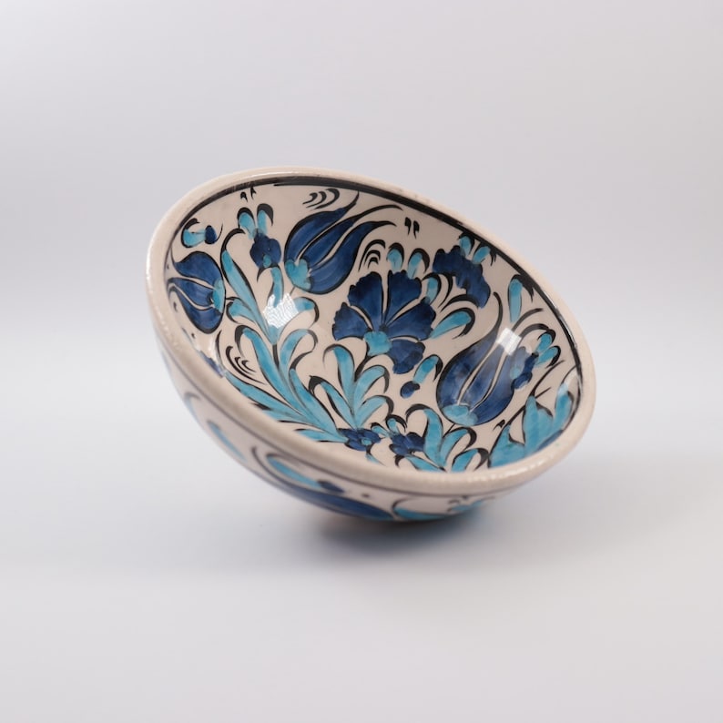 Puede incluir: Un cuenco de cer&aacute;mica blanca con un dise&ntilde;o floral azul y turquesa. El cuenco est&aacute; pintado a mano con detalles intrincados y es perfecto para servir aperitivos o postres.