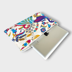 Könnte beinhalten: Eine weiße iPad-Hülle aus Stoff mit einem farbenfrohen Blumen- und Paisley-Muster. Die Hülle hat einen Reißverschluss und das iPad ist teilweise in die Hülle gesteckt.