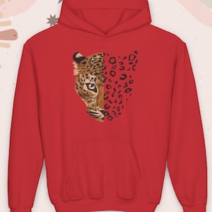 May include: A red hooded sweatshirt featuring a half-leopard face design. The leopard's face is detailed with brown, black, and tan markings, while the other half of the design features red leopard spots.