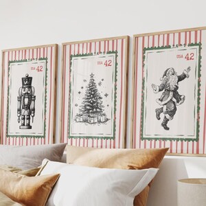 Pode incluir: Três impressões de arte de Natal emolduradas. Cada impressão apresenta uma ilustração a preto e branco: um quebra-nozes, uma árvore de Natal com presentes e o Pai Natal. As molduras têm uma borda listrada vermelha e branca com uma moldura verde e o texto "USA 42".