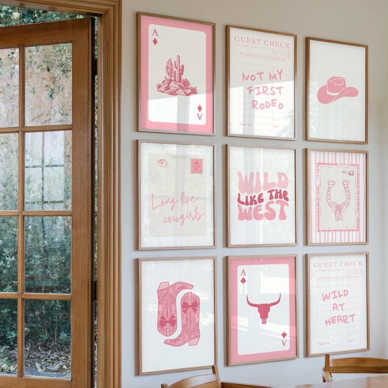 May include: A collection of framed art prints with a Western theme. The prints feature pink and white designs, including a cactus, cowboy hat, horseshoe, and the phrases "Wild Like the West" and "Not My First Rodeo."