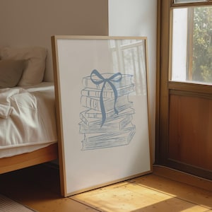Peut inclure: Une affiche encadrée représentant une pile de livres ornée d'un ruban bleu. L'illustration est en bleu clair sur fond blanc. Le cadre en bois ajoute une touche chaleureuse à l'œuvre, idéale pour une chambre ou un bureau.