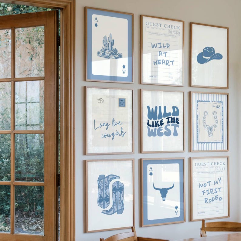 May include: A collection of framed art prints with a Western theme. The prints feature blue and white illustrations of a cactus, cowboy hat, horseshoe, and playing cards. Text includes "Wild at Heart", "Long live cowgirls", and "Wild like the West".