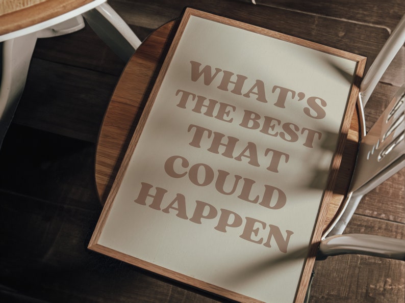 May include: A framed print with the text "What's the best that could happen" in a light brown colour on a cream background.
