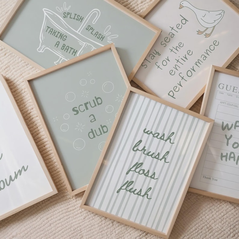 K&ouml;nnte beinhalten: Eine Sammlung gerahmter Badezimmer-Kunstdrucke mit hellen Holzrahmen. Die Drucke zeigen S&auml;tze wie "wash, brush, floss, flush" und "scrub a dub" in handschriftlichem Stil. Die Farbpalette umfasst Gr&uuml;n-, Wei&szlig;- und Graut&ouml;ne.