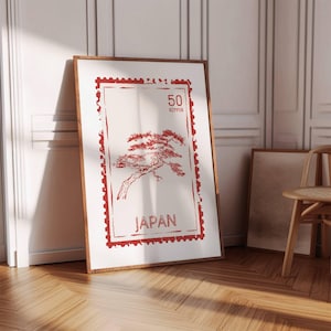 Puede incluir: Lámina artística enmarcada con una ilustración roja de un bonsái dentro de un diseño de sello postal. La impresión incluye el texto "50 NIPPON" y "JAPAN" en rojo. El marco es de color madera oscura.