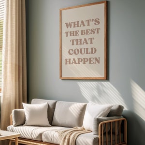 May include: A framed print with the text "WHAT'S THE BEST THAT COULD HAPPEN" in a light brown colour on a beige background. The frame is a light wood colour. The print is hanging on a light blue wall.