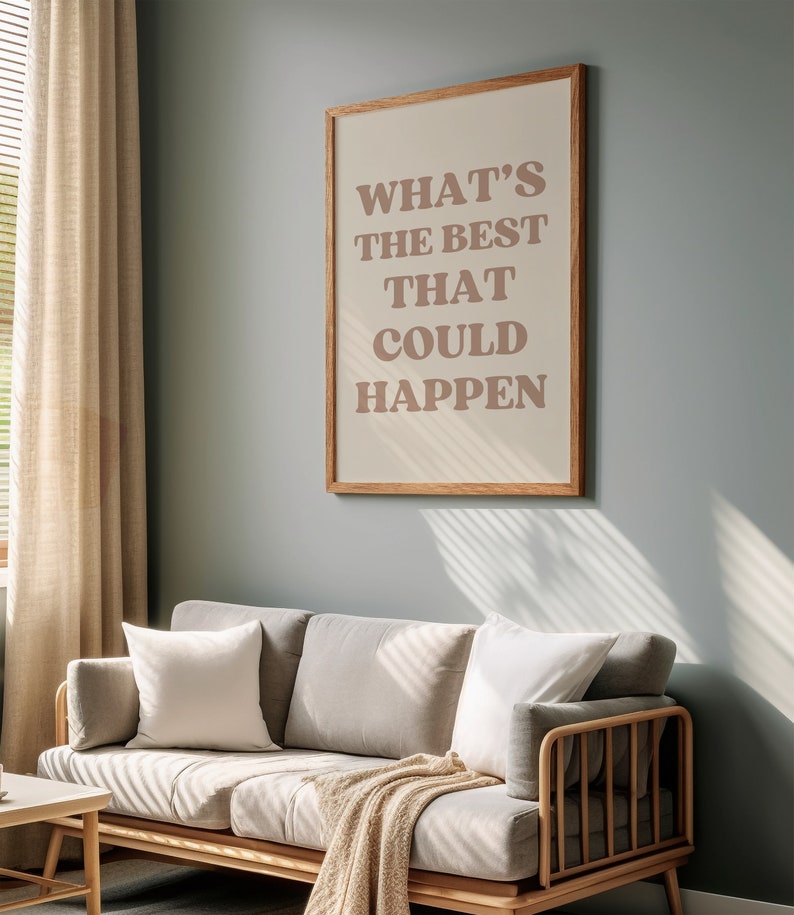 May include: A framed print with the text "WHAT'S THE BEST THAT COULD HAPPEN" in a light brown colour on a beige background. The frame is a light wood colour. The print is hanging on a light blue wall.
