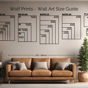 May include: A wall art size guide from Wolf Prints, featuring various aspect ratios and sizes, including 11 x 14 inches and 5 x 7 inches. The guide is displayed above a brown leather sofa, with a small potted tree to the right. The text reads "Wolf Prints - Wall Art Size Guide".