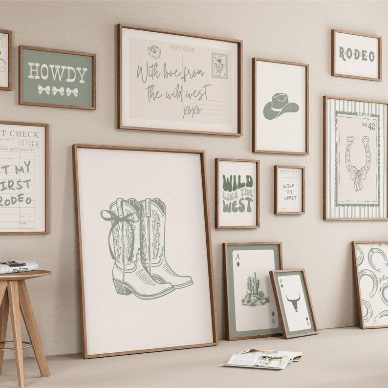 May include: A gallery wall collection of framed art prints featuring sage green and cream western-themed illustrations. Designs include cowboy boots, a postcard, a rodeo sign, a horseshoe, a cactus, a bull skull, and text like Howdy and Wild Like the West.