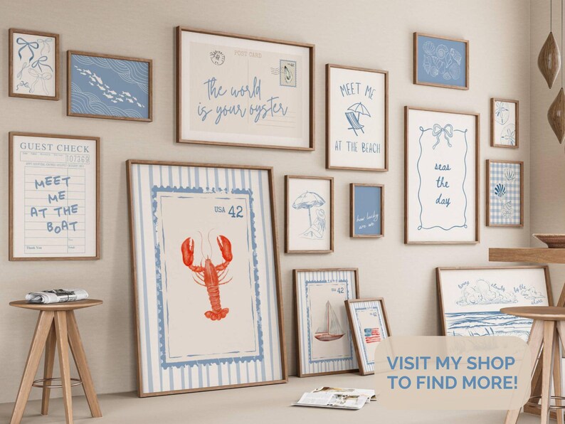 May include: A collection of framed art prints with a coastal theme. The prints feature nautical illustrations, including a lobster, sailboat, and beach scenes. The color palette includes blue, white, and brown tones. Some prints have text like "Meet Me at the Beach."