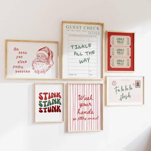 May include: A collection of framed Christmas-themed art prints. The prints feature humorous text and illustrations, including Santa Claus, a guest check, and a postcard. The color palette includes red, green, and white.
