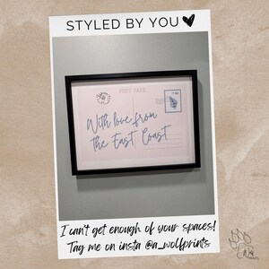 May include: A framed print featuring a vintage postcard design with the text "With love from The East Coast." The print includes a postage stamp and the words "Post Card." The frame is black, and the background is a light gray.
