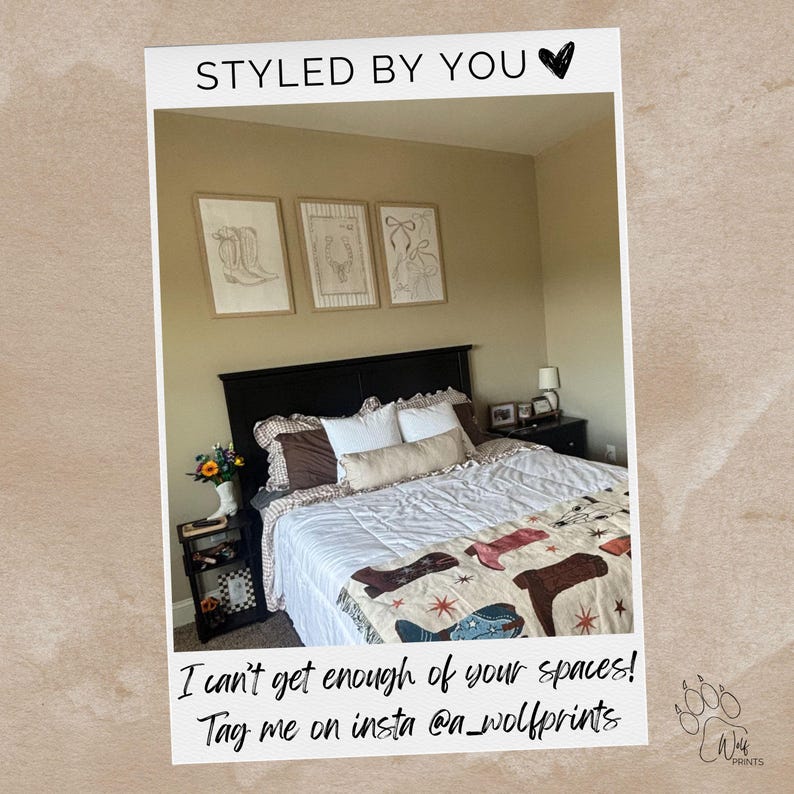 May include: A bedroom featuring a black headboard, white bedding, and a throw blanket with a cowboy boot pattern. Three framed line art prints hang above the bed. Text reads: STYLED BY YOU, I can't get enough of your spaces! Tag me on insta @a_wolfprints.