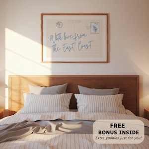 May include: A framed postcard print with the text "With love from The East Coast" in light blue script. The print hangs above a bed with striped pillows and a gray blanket. A bonus offer is visible at the bottom.
