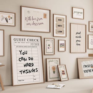 May include: A collection of framed wall art with inspirational quotes and designs. The art includes phrases like "You Can Do Hard Things" and "Great Minds Grow Here." The frames are a light brown color, and the overall theme is motivational and educational.