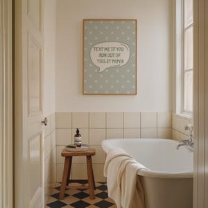 K&ouml;nnte beinhalten: Ein Badezimmer mit einem gerahmten Druck mit der Aufschrift "TEXT ME IF YOU RUN OUT OF TOILET PAPER". Der Druck h&auml;ngt &uuml;ber einer Badewanne. Ein kleiner Holzschemel h&auml;lt eine Flasche und eine B&uuml;rste. Der Boden hat ein schwarz-wei&szlig;es Schachbrettmuster.