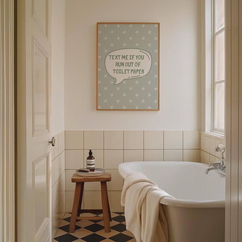 K&ouml;nnte beinhalten: Ein Badezimmer mit einem gerahmten Druck mit der Aufschrift "TEXT ME IF YOU RUN OUT OF TOILET PAPER". Der Druck h&auml;ngt &uuml;ber einer Badewanne. Ein kleiner Holzschemel h&auml;lt eine Flasche und eine B&uuml;rste. Der Boden hat ein schwarz-wei&szlig;es Schachbrettmuster.