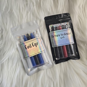 May include: Two clear and black resealable pouches containing sets of taper candles. The left pouch is labeled Evil Eye with blue, black, and white candles. The right pouch is labeled Return to Sender with black and red candles.