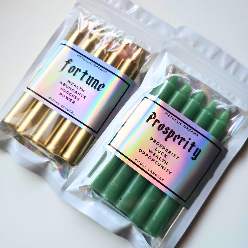 May include: Two clear plastic pouches containing ritual candles. The left pouch holds gold candles with a label reading Fortune, Wealth, Abundance, Success, Power. The right pouch holds green candles with a label reading Prosperity, Luck, Wealth, Opportunity.