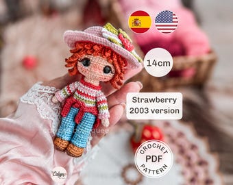 May include: A 14cm tall crocheted doll with red hair, wearing a pink hat with green and red accents, a striped long-sleeve shirt, blue pants, and brown shoes. The doll is labeled as the Strawberry 2003 version and is a crochet PDF pattern.