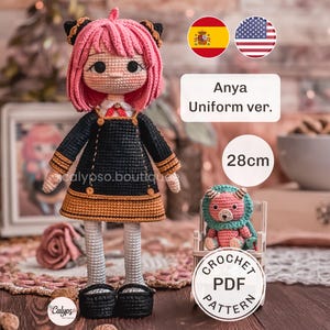 Puede incluir: Muñeca tejida a mano con cabello rosa y accesorios negros, viste un vestido negro con detalles dorados y cuello blanco con lazo rojo. La muñeca mide 28cm de altura. A su lado hay una pequeña criatura tejida. Texto: Anya Uniform ver.