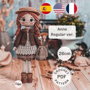 Puede incluir: Una muñeca de ganchillo con pelo rojo trenzado, lleva un sombrero marrón, una chaqueta marrón oscuro, un vestido gris claro y botas marrones. La muñeca sostiene un pequeño bolso marrón. El texto incluye 'Anne Regular ver.', '26cm' y 'CROCHET PDF PATTERN'.