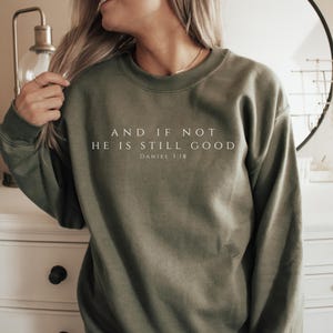 Könnte beinhalten: Ein grüner Pullover mit dem Aufdruck "AND IF NOT HE IS STILL GOOD DANIEL 3:18" in weiß.