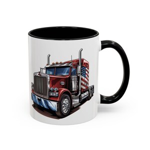 May include: A white ceramic coffee mug with a black rim and handle. The mug features a cartoon illustration of a red semi-truck with an American flag on the side.