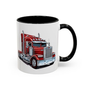 May include: A white ceramic coffee mug with a black rim and handle. The mug features a cartoon illustration of a red articulated lorry.