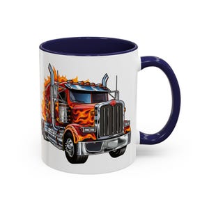 May include: A white ceramic coffee mug with a blue rim and handle. The mug features a cartoon illustration of a red, orange, and yellow semi-truck with flames on the side.